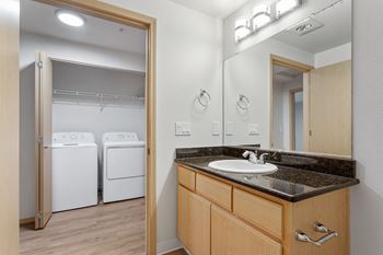 A bathroom with a sink, mirror, and two washing machines.